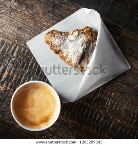 Cappuccino and croissant for breakfast on dark rustic wooden table with copy space. Flat lay. Top view