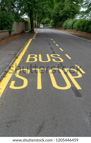 Bus stop sign painted in yellow on road surface