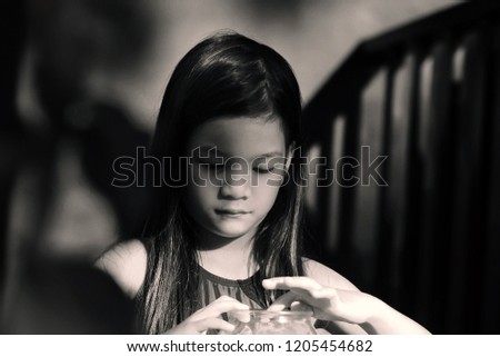 Retro color tone image of 6 years old Asian little girl in the natural light and shadow. Candid shot of a long hair girl in morning or sunset light.