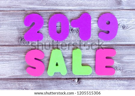 Sign sale 2019 made of colorful letters on wooden background.