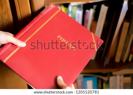 close up hand search and take the red photo album on the book shelf
