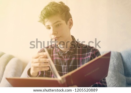 smiling young person watching the family photo album at home on the sofa