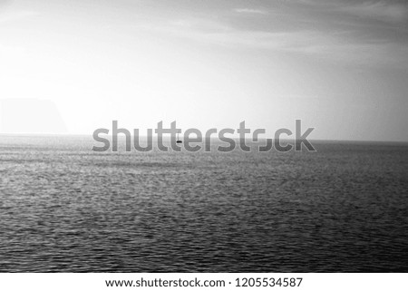 beautiful bright black and white photo of ocean horizon with small boat