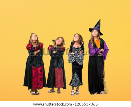 Set of Little girl dressed as a vampire for halloween holidays stand and looking up on orange background