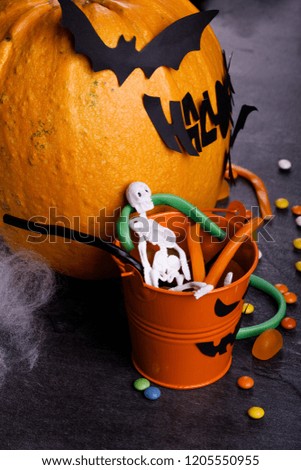 Halloween pumpkin with decorations, candies, and spiderweb on a dark background. The concept of autumn holidays.