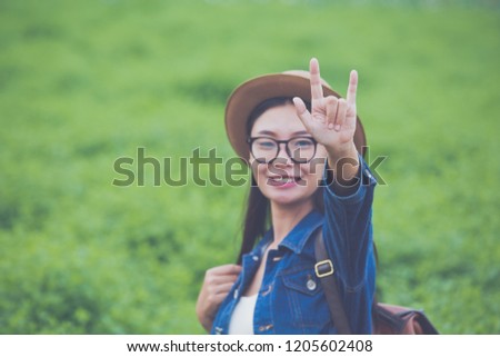 Woman traveler with backpack  hat and looking at lies on a meadow in the mountains.