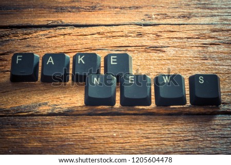 Word "Fake News" written with the keys of the computer keyboard on the wooden background.