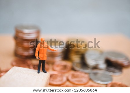 Miniature people, engineer standing on stack coins background using as finance, industry and business concept