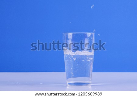 Water splashing from glass isolated on a blue background.