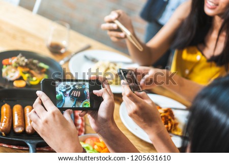Close up hands of woman taking photo of dinner food on the table