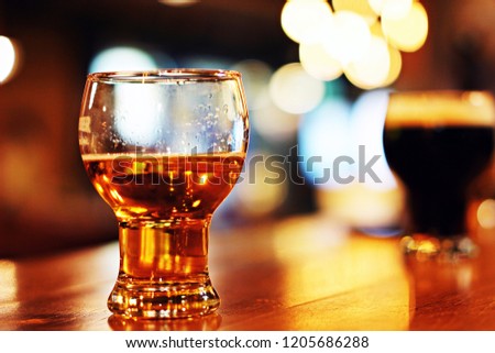 A glass of draft or craft beer, bokeh background from a lighting of night club, depth of picture with copy space.