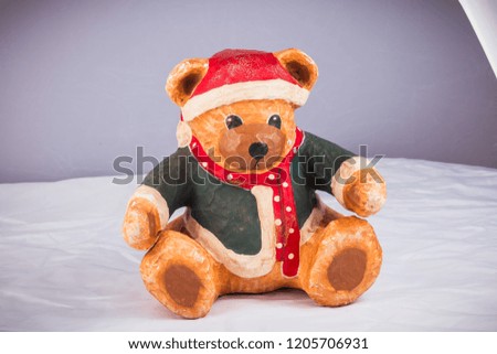 little bear dressed for Christmas is taking a photo in studio