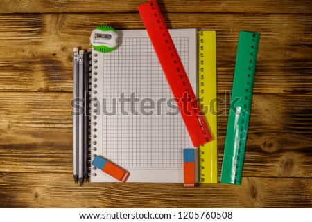 Set of school stationery supplies. Blank notepad, rulers, pencils, erasers and sharpener on wooden desk. Top view