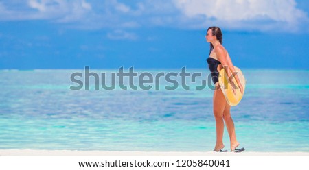 Beautiful surfer woman ready to surfing in turquoise sea, on stand up paddle board at exotic vacation