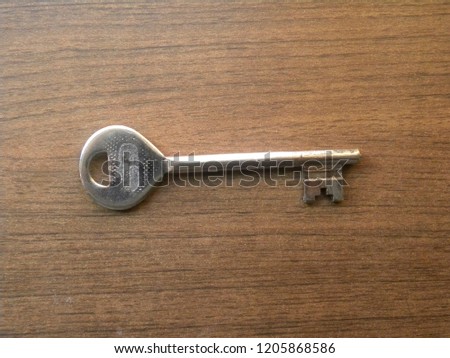 Big metal door key kept on wooden table