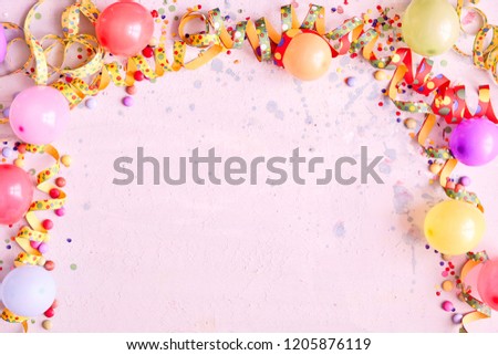 Carnival balloon border with colorful streamers, candy and confetti on a pink background with copy space and splashes texture