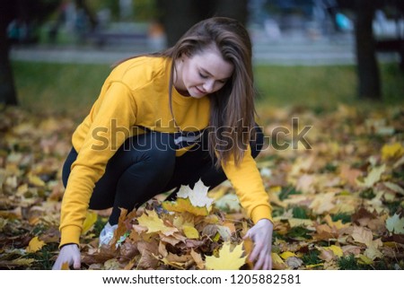 Pretty young woman throwing leaves in a park, enjoying