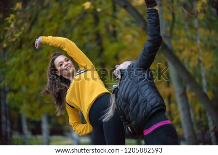 Autumn photo of sporty women stretching and doing yoga in forest at morning against background of trees.