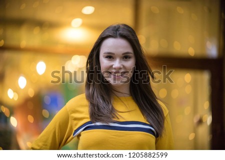 Outdoor fashion photo of young beautiful lady in yellow sweater lights in backgrond
