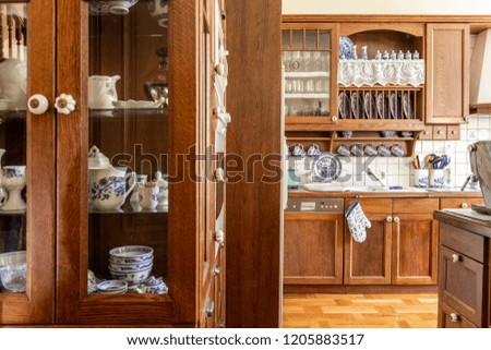 Old fashioned wooden cabinets with white and cobalt blue china in kitchen interior. Royalty-Free Stock Photo #1205883517