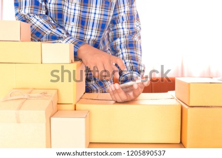 Businessman working with mobile phone and packing brown parcels box at home office. hands seller prepare product ready for deliver to customer. Online selling, e-commerce Start up shipping concept.