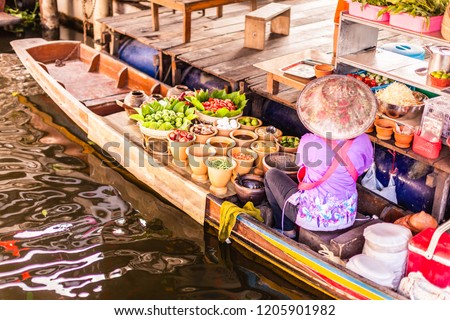 An unrecognizable Thai food peddler selling fruit and vegetables on her boat in the Damnoen Saduak floating market Royalty-Free Stock Photo #1205901982