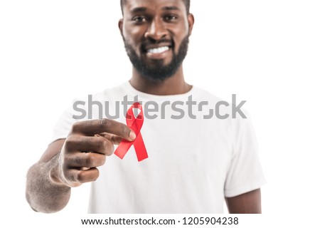 close-up shot of african american man in blank white t-shirt with aids awareness red ribbon looking at camera isolated on white Royalty-Free Stock Photo #1205904238
