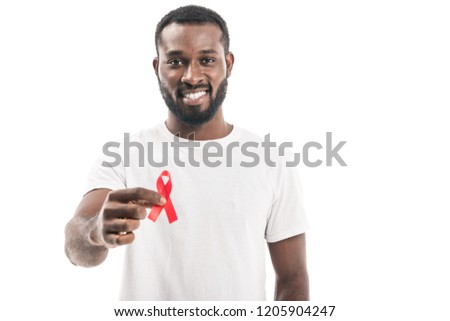 smiling african american man in blank white t-shirt holding aids awareness red ribbon and looking at camera isolated on white Royalty-Free Stock Photo #1205904247