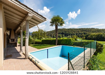 Villa with pool and surrounded by green lawn on a summer day. Nobody inside