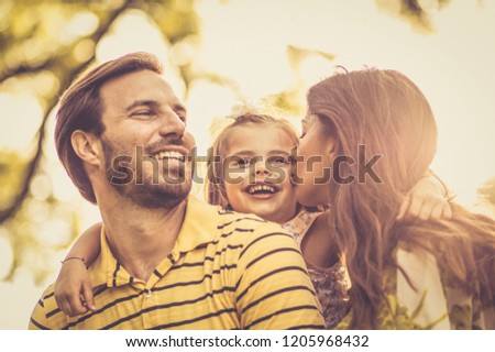 One kiss for cute little girl. Little girl with her parents enjoy in nature. 