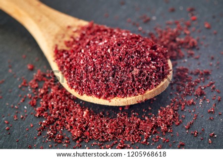 Close up of ground sumac spice powder in wooden spoon Royalty-Free Stock Photo #1205968618