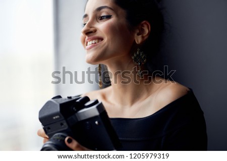 woman with a camera smiles and looks out the window                       