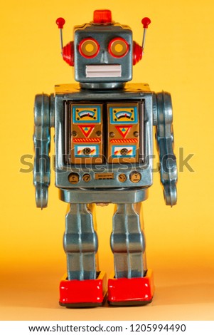 Vintage tin robot toy isolated on a yellow background.