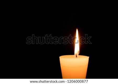 Portrait of one light candle burning brightly on black background. Close-up flame.