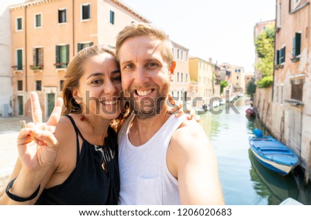 Happy couple taking a selfie with smart mobile phone in the canals of Venice the famous european city in Italy in summer holidays Tourism Traveling around europe vacation love and honeymoon concept.
