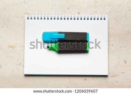 Blue and green highlighters on blank notepad paper sheet flat lay on a desk