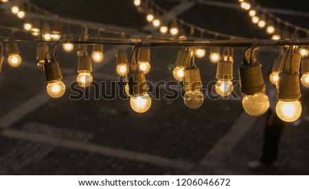 Festival garland light bulbs hanging over outdoor  shopping area copy space