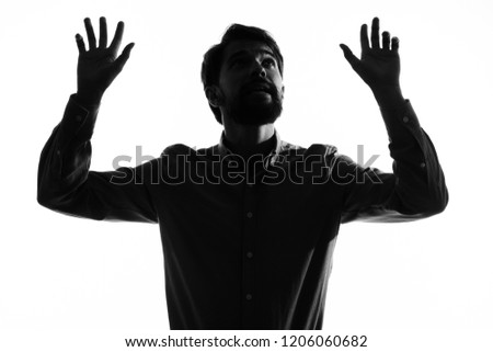 dark silhouette of a man with arms raised                       