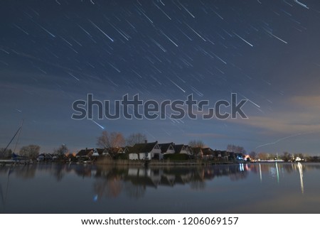 Stars seem to fall down and form star trails with meteor effect, created as the earth rotates, in Seepark Weiden at Lake Neusiedlersee in Austria at night.