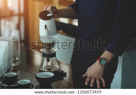 Barista pouring hot water to coffee dripper in cafe with dark tone image, cafe coffees background for create selling content