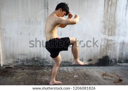 Outdoor workout/exercise concept. Young athlete fitness muscular man training. Doing the Thai boxing - Muay Thai.