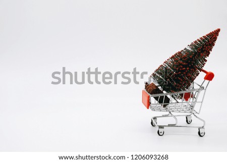 Mini shopping cart with a Christmas tree isolated on white background.