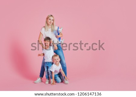 Beautiful blonde mom with two happy sons. Young woman and two baby boys, pink background