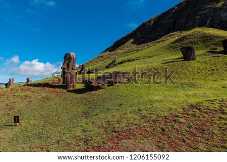 Hill on Easter Island with Moai statues facing inward; tourists climbing the hill in the background.