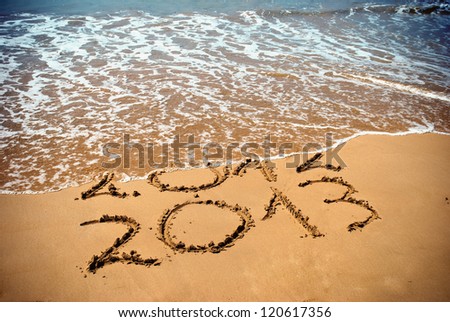New Year 2013 is coming concept - inscription 2012 and 2013 on a beach sand, the wave is covering digits 2012 Royalty-Free Stock Photo #120617356