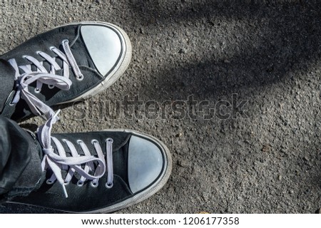 black sneakers on a background of asphalt road