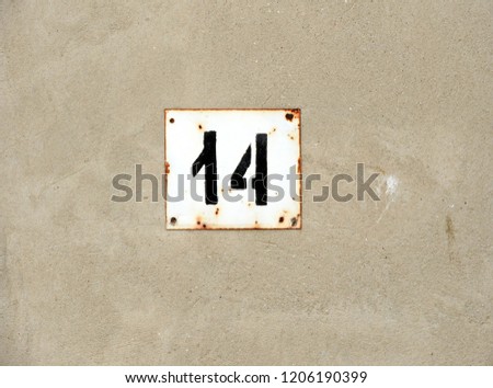 
Number fourteen on a beige wall.				