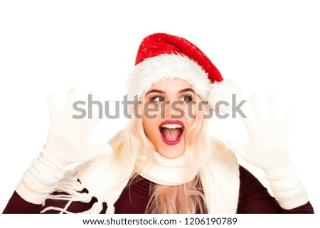 Attractive smiling young girl dressed in Santa's hat making faces and dreams about gifts. Christmas and New Year advertising concept isolated on abstract blurred white background with blank copy space