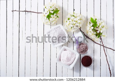skin care product samples and cherry blossom on white wood table background