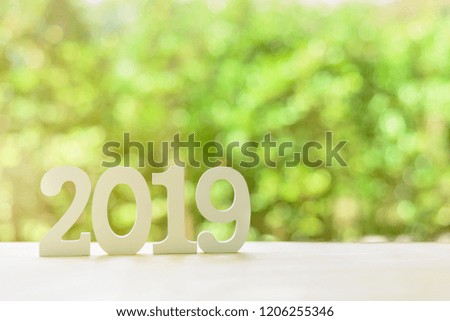 2019 happy new year, green nature theme concept : Number 2019 white wood cut on a desk table in a public garden, depicts new bloom spreads fragrance, beauty and freshness added into new bright life